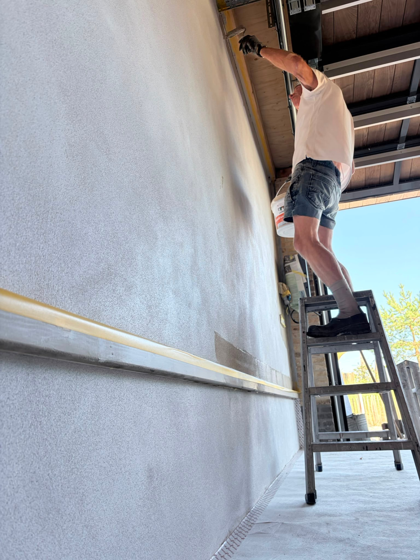 Schilderwerk hoog bij een garagedeur vanaf een trapje