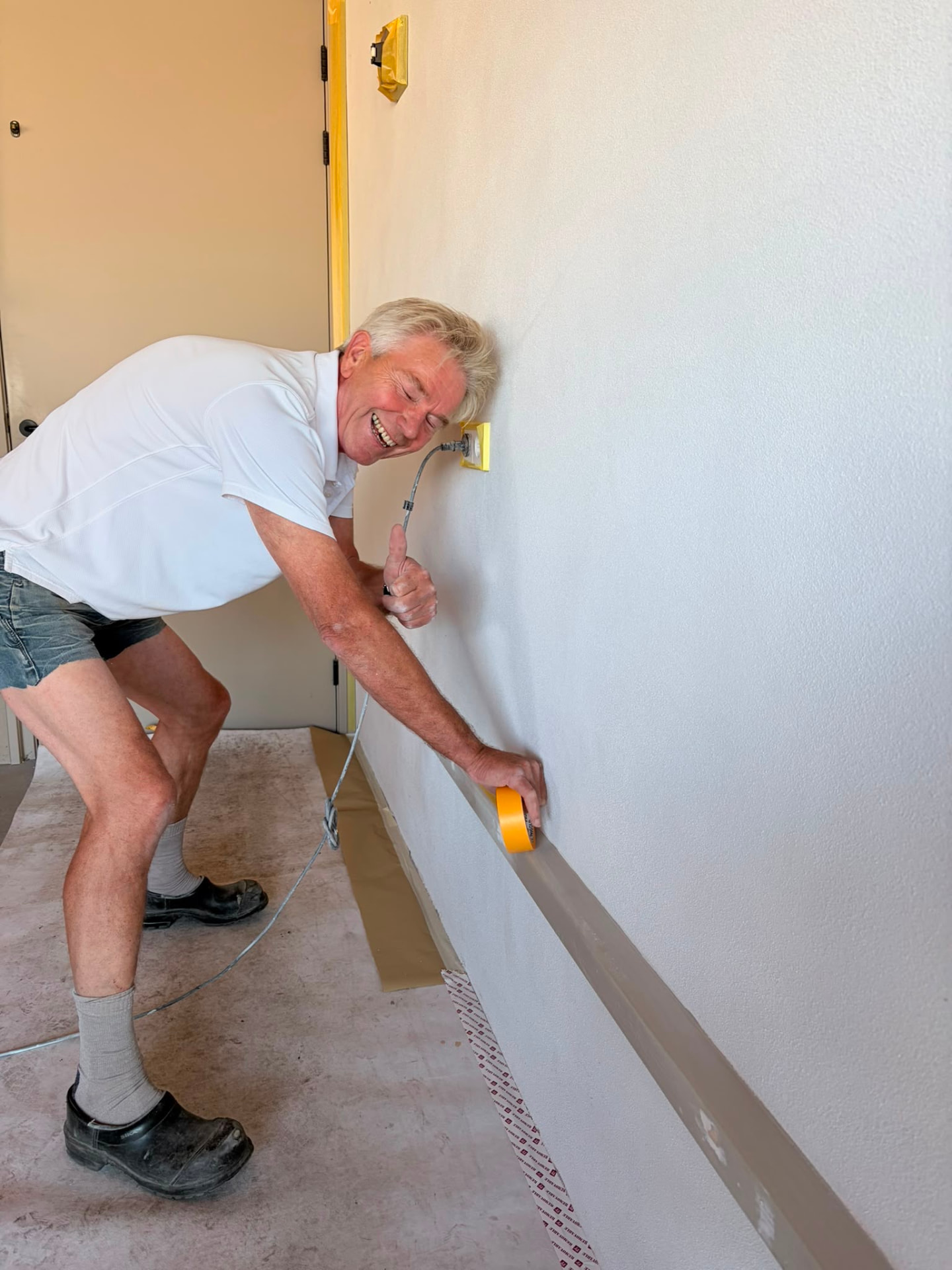 Meester plakt een wand netjes af met tape