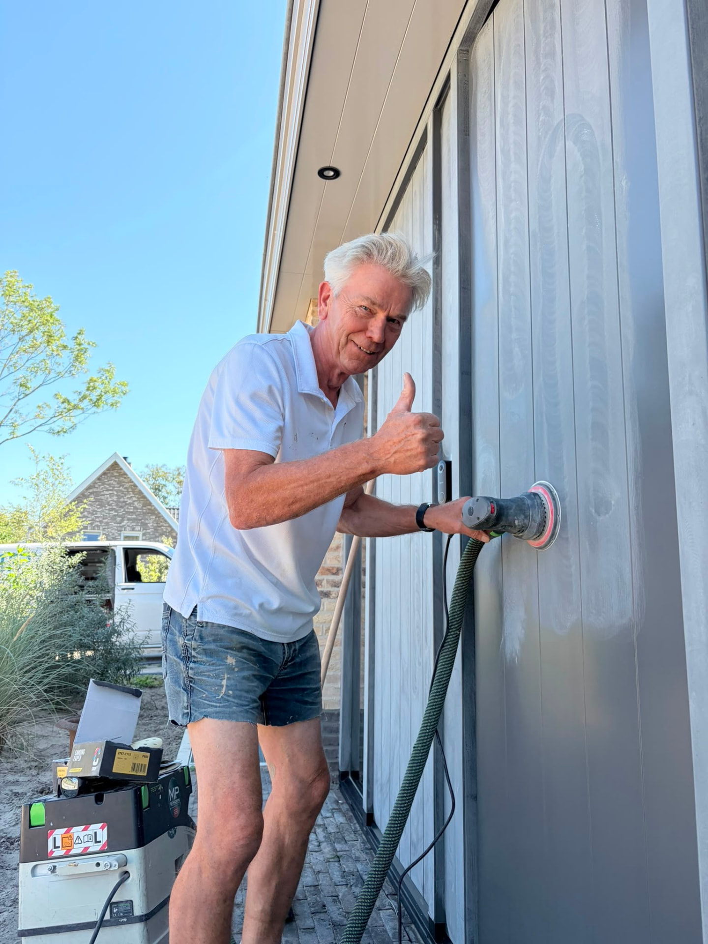Meester schuurt een deur machinaal voor het schilderen